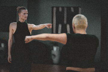 Two dancers rehearsing with arms extended toward each other
