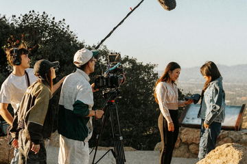 Crew filming two performers on the hilltop at dusk