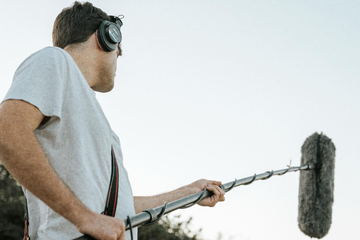 The boom operator in headphones against the sky