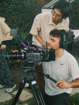 Javi at the camera on a tripod with the assistant camera leaning in above him