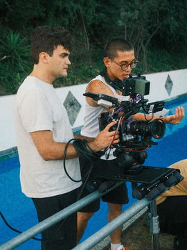 Javi operating the camera on a slider beside a pool while the assistant pulls focus