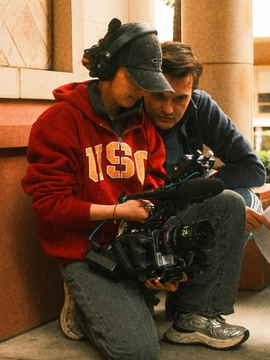 Javi beside the camera operator, both crouched over the camera