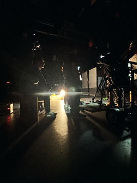 The stage in near darkness with one practical light on the floor