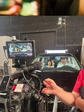 A monitor on the bonnet showing two actors inside the picture car