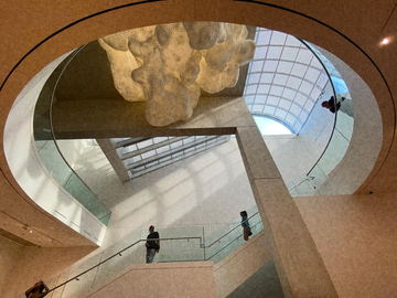 A circular atrium with a skylight and two figures on the ramp below