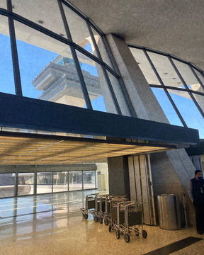 A terminal interior with tall glazing and a control tower outside
