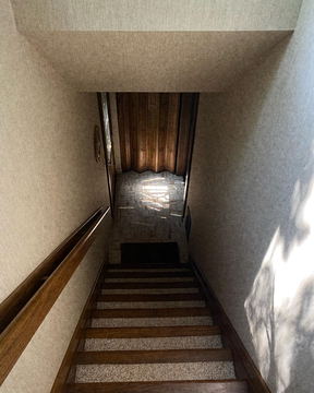 A narrow stairwell climbing toward a lit landing