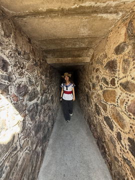 A figure walking away down a narrow stone tunnel